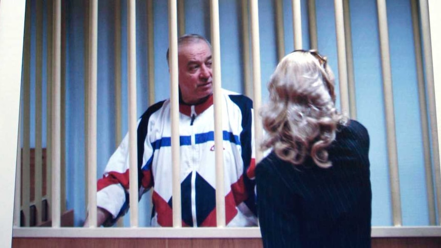 Sergei Skripal is seen on a monitor talking to his lawyer from behind bars.