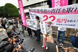 Journalists and photographers surround protesters holding banners and placards outside a courthouse in Japan
