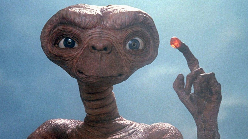 An alien holds up a lit finger