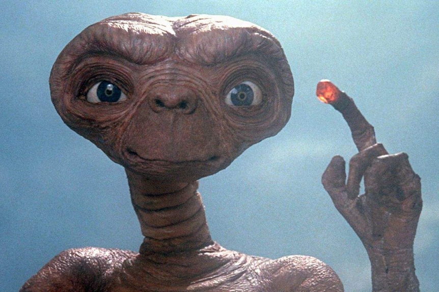 An alien holds up a lit finger