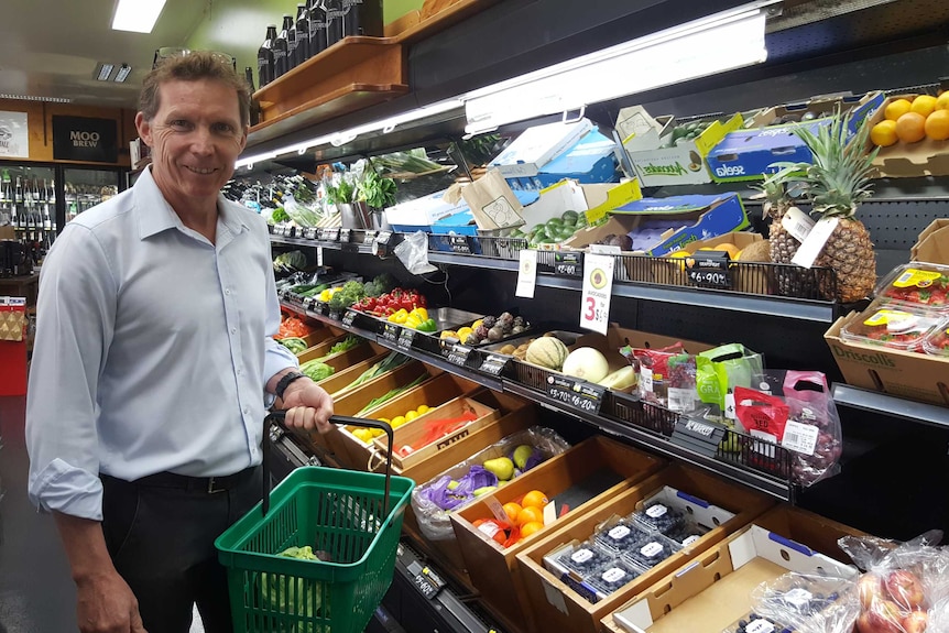 Gary Fettke stands next to the fruit and vegetable section in a grocery store.