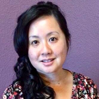 A woman stands in front of a purple wall.