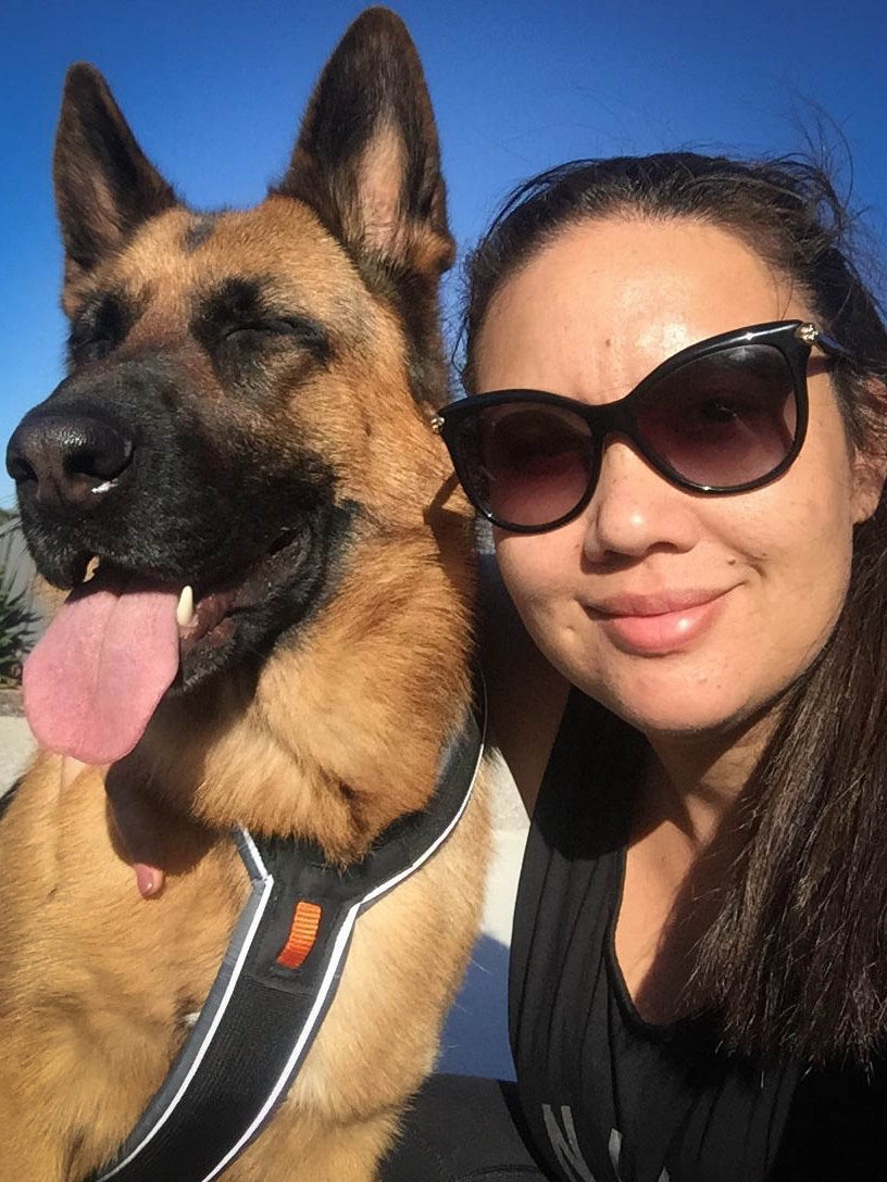 Woman with brown hair and sunglasses posing next to german shepherd dog