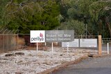 A sign at the Perilya mine in north Broken Hill in front of a fence and green trees