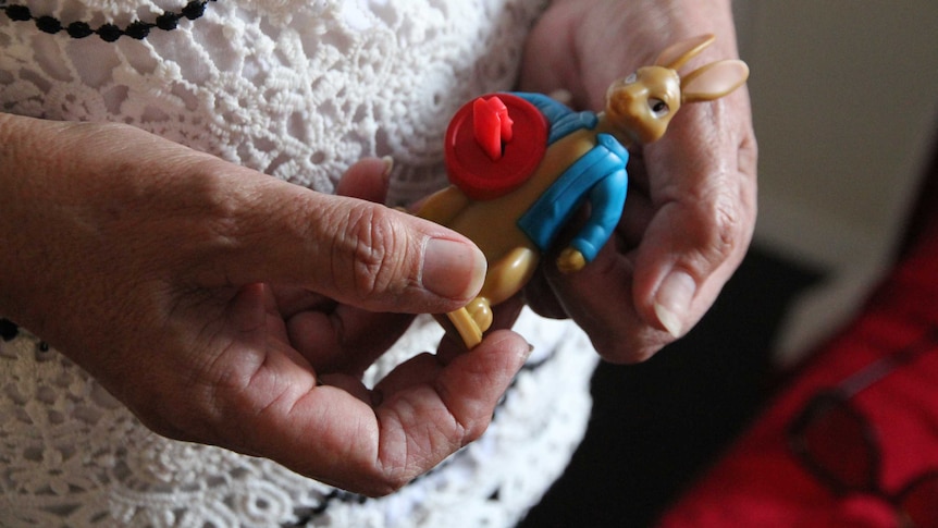 A older woman's hands holds a small Peter Rabbit toy