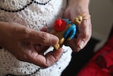 A older woman's hands holds a small Peter Rabbit toy