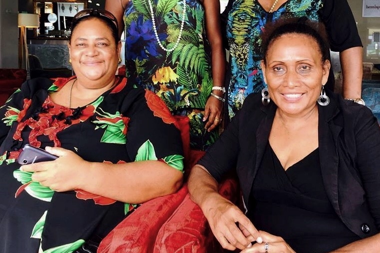 Andrina Thomas (left) and Manina Packete (right) sit next to each other on two lounge chairs.