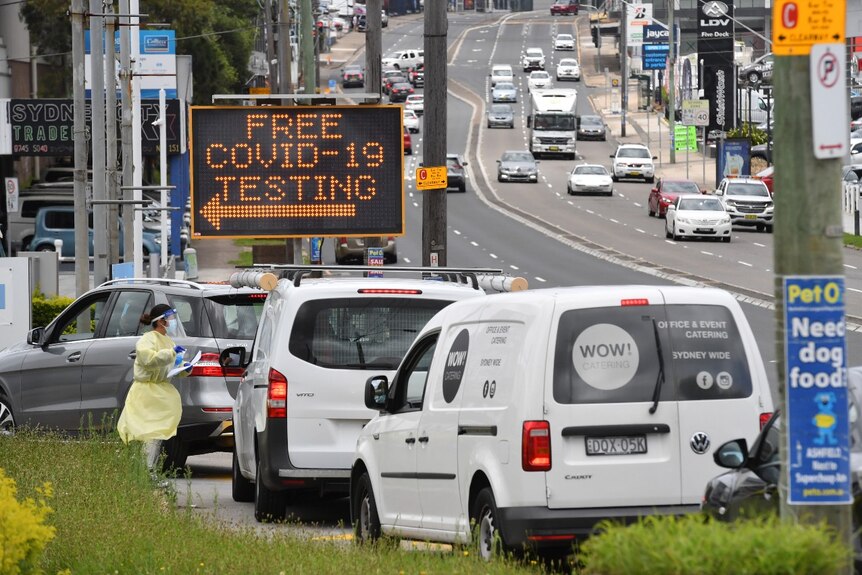 Cars line up in front of an electronic sign that reads: "Free COVID-19 testing".