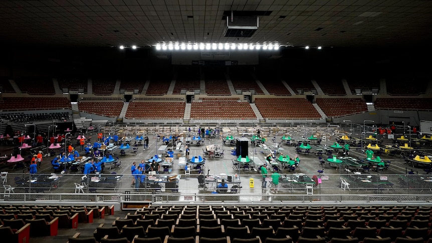 Colored tables dot the floor of a giant auditorium that's otherwise empty 