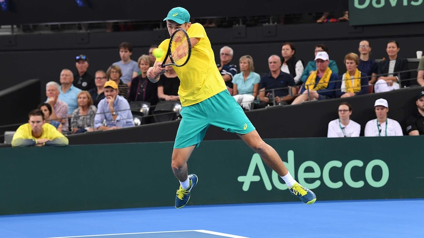 Alex de Minaur in mid-air as he plays a double-fisted backhand to Alexander Zverev in the Australia vs Germany Davis Cup tie.