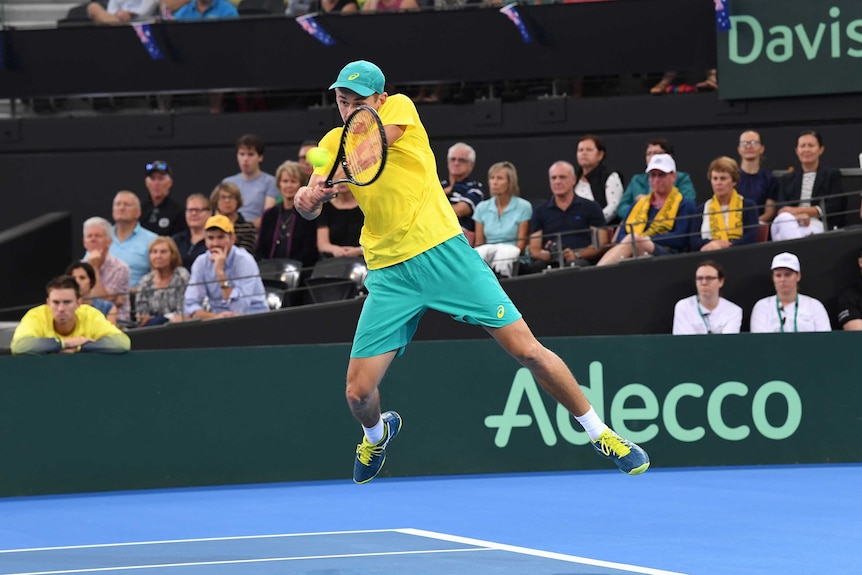 Alex de Minaur in mid-air as he plays a double-fisted backhand to Alexander Zverev in the Australia vs Germany Davis Cup tie.