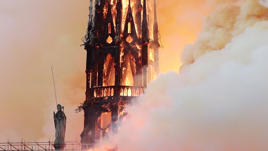 Flames and smoke engulf a gothic cathedral spire