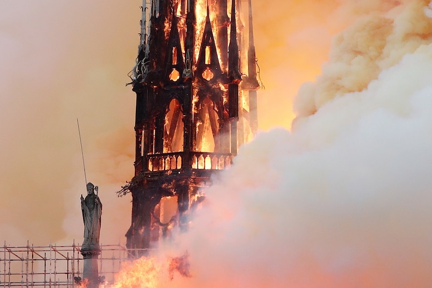 Flames and smoke engulf a gothic cathedral spire