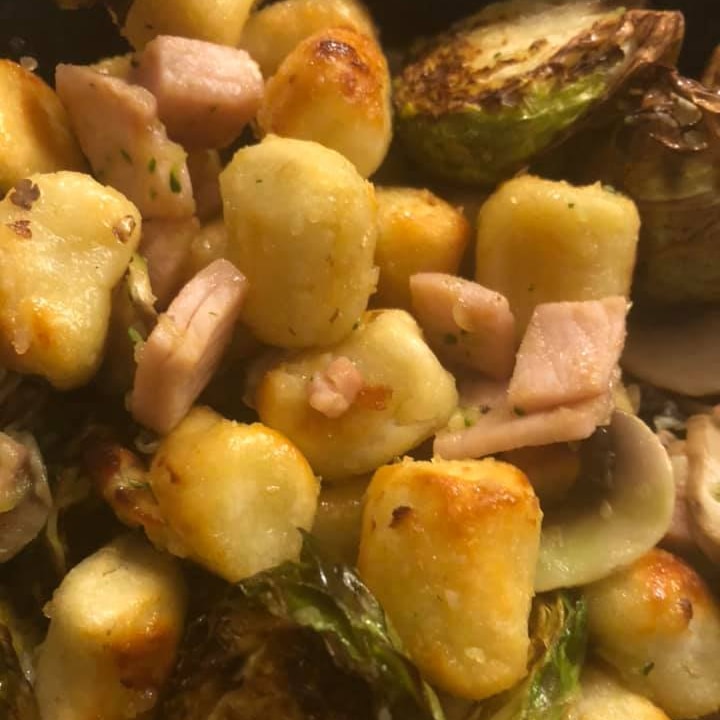 A close up of gnocchi, seared brussels sprouts and small bits of bacon.