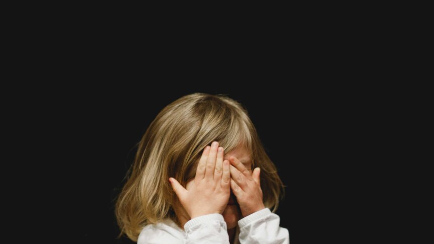A child covering her face