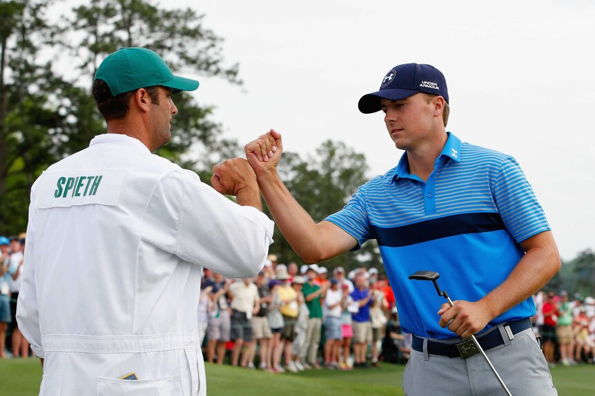 Spieth celebrates with his caddy at the Masters