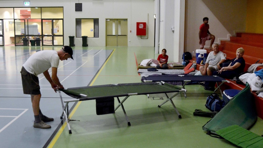 A man sets up a folding bed at an evacuation centre in Cooktown.