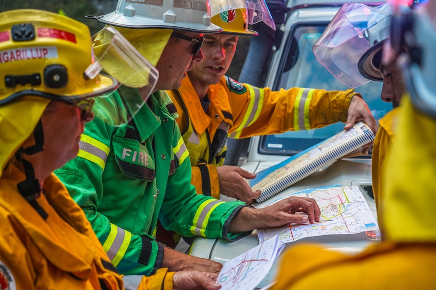 A group of firefighters look at a map