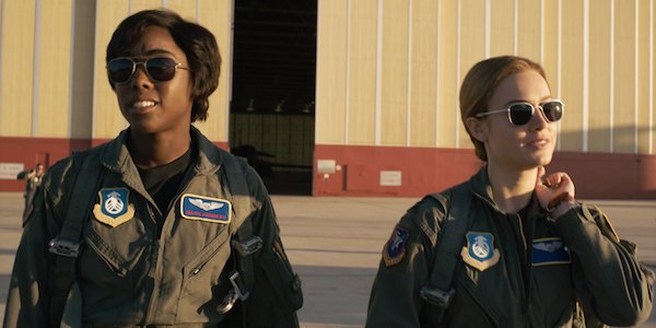 Two female fighter pilots walk from a hangar in a still from a film.