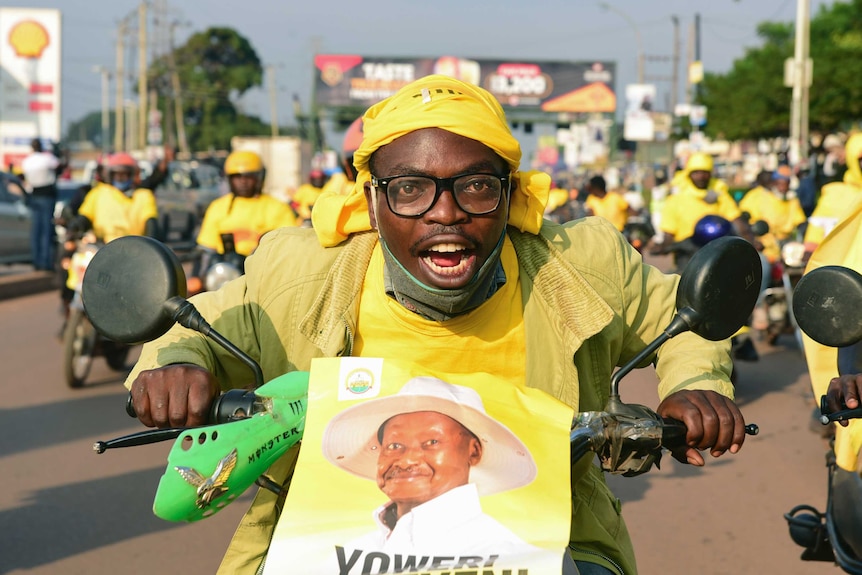 A man rides a motorcycle dressed in yellow with a picture of Ugandan President Yoweri Kaguta Museveni on the front.