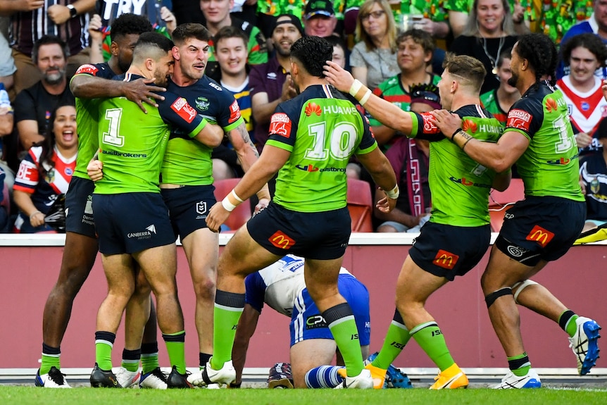A Canberra Raiders player accepts congratulations as teammates run to join him after a try.