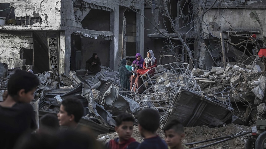 Palestinian girls sit amidst the extensive rubble of what were once homes in Gaza City.