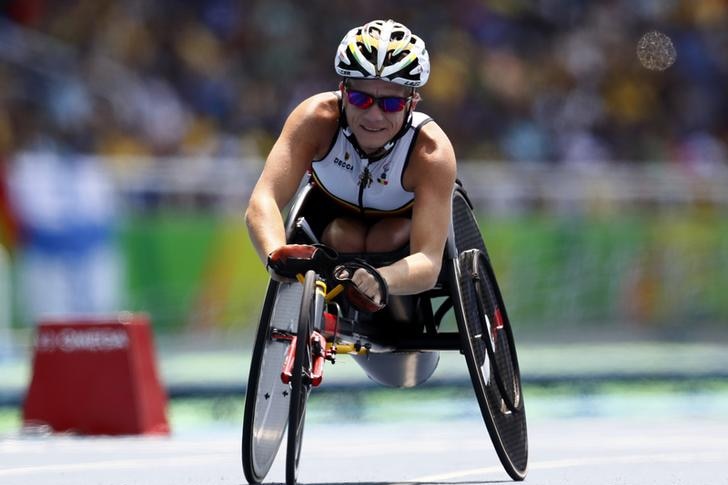 Marieke Vervoort appears in a wheelchair during the women's 100 metre race. She is on the track and a blurry crowd is in back.