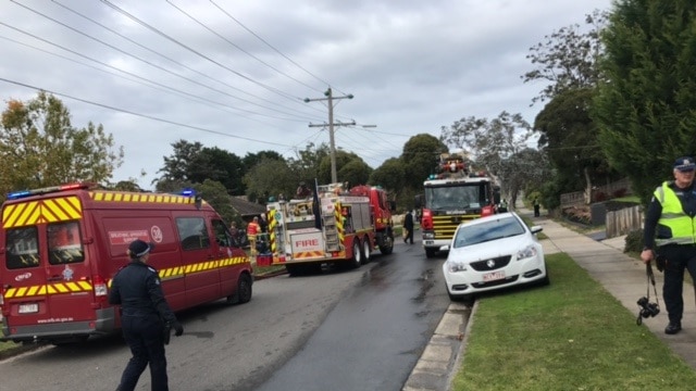 A policewoman walks past a fire truck at the scene of a fatal house fire in Bundoora.