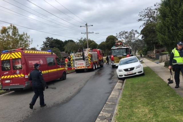 A policewoman walks past a fire truck at the scene of a fatal house fire in Bundoora.