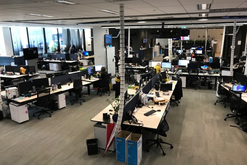 Aerial shot rows of mostly empty desks with only a few people at work.