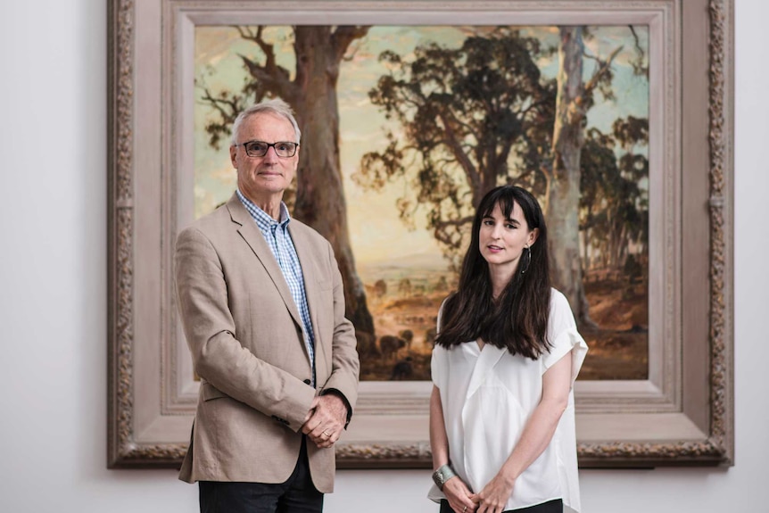 A man and woman standing in front of Hans Heysen's painting Droving into the light