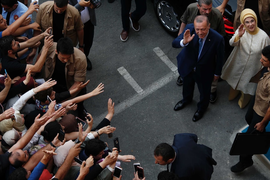 Group of supporters reach out to Tayyip Erdogan who waves alongside his wife