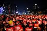 Large crowd of protesters waving signs through streets of Seoul. December 31, 2016.