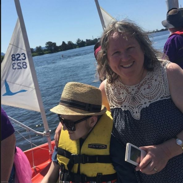 A mother with her arm around her son on a sailing boat