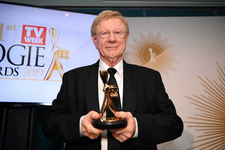 Kerry O'Brien looks at the camera as he holds his hall of fame Logie Award.