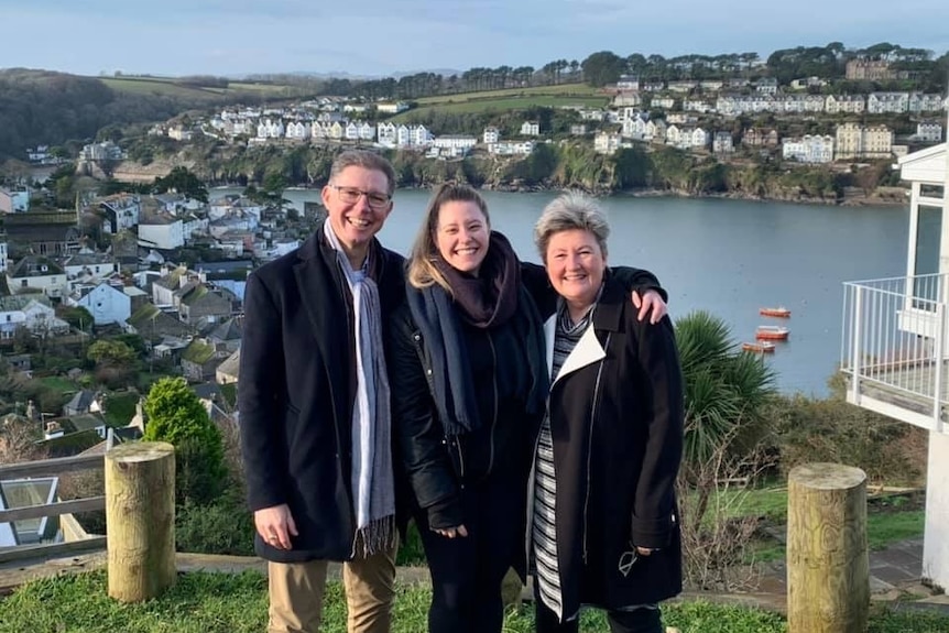 Emily Regan with two people in front of a scenic area.