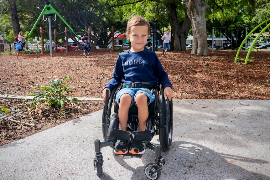 zach in his wheelchair with a playground behind him