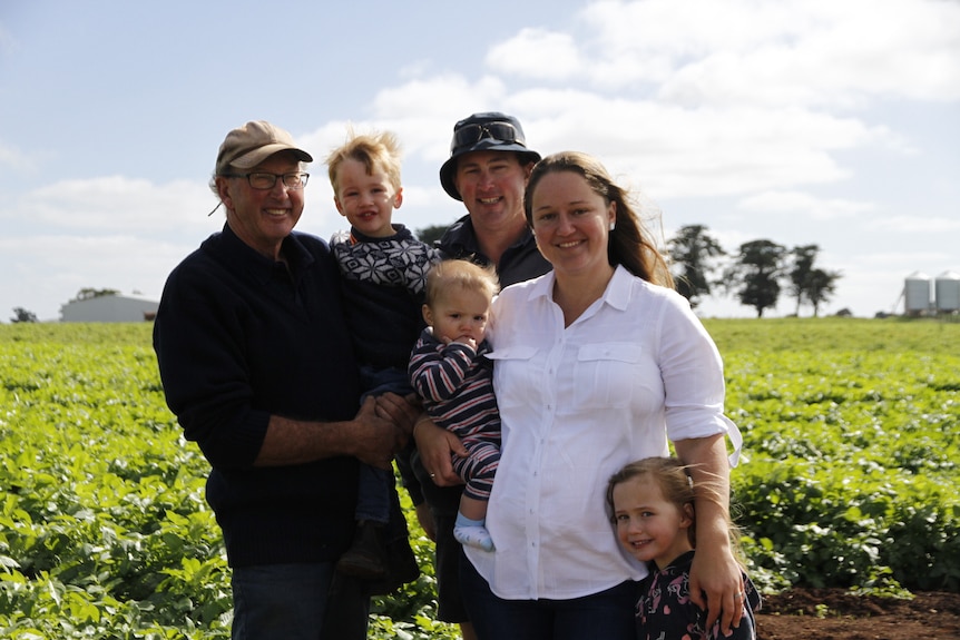 Three generations of one family, three children, the parents and grandfather stand in a potato crop north of Ballarat.