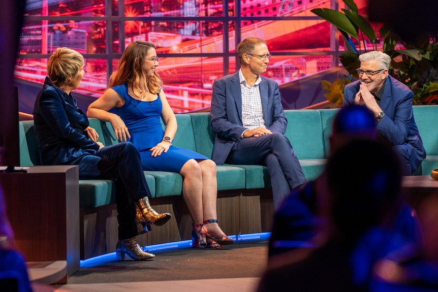 Two women and two men sitting on a circular couch in a TV studio.