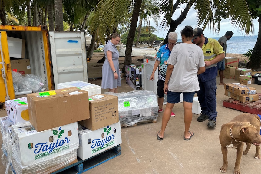 People stand around looking at packages outside a container