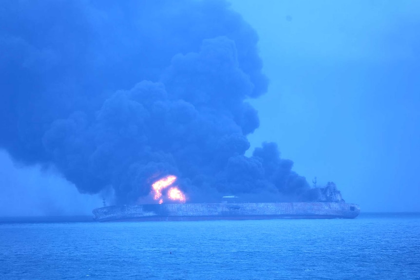 Smoke and flames are seen pouring from a tanker in the ocean.