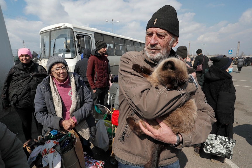 People gather in a car park as they flee their city with all their belongings. 