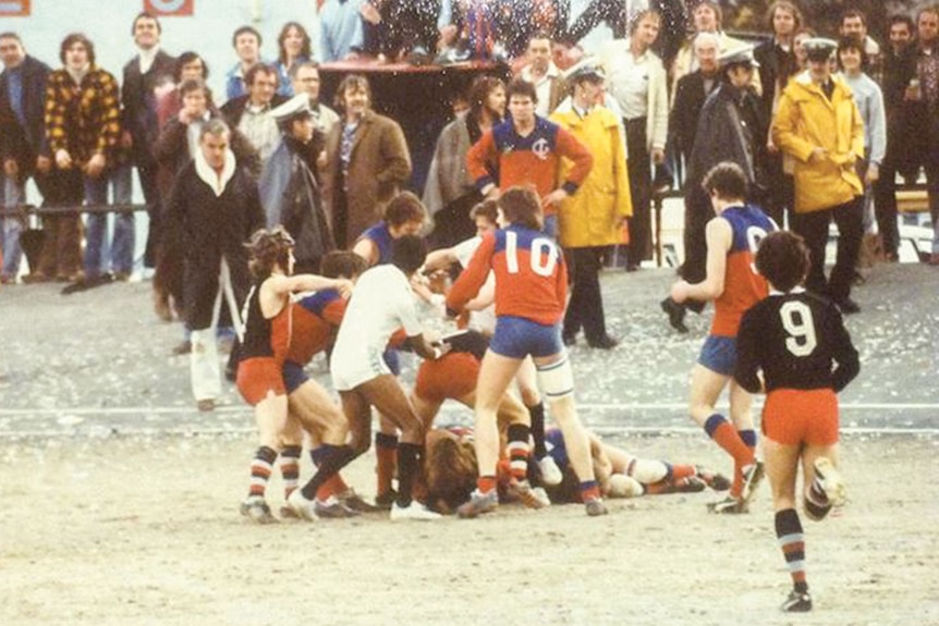 A number of footballers fighting on a gravel football ground during a match