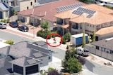 An aerial shot of a suburb with a person riding a scooter highlighted by a red ring