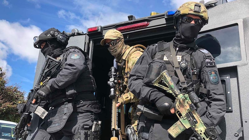 Special Emergency Response Team officers emerging from the back of a troop carrier