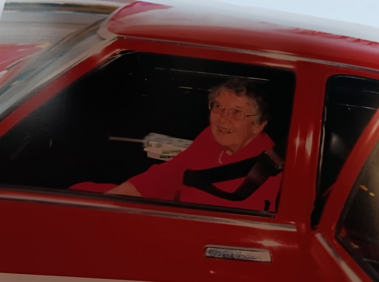 An older lady in a red Kingswood car