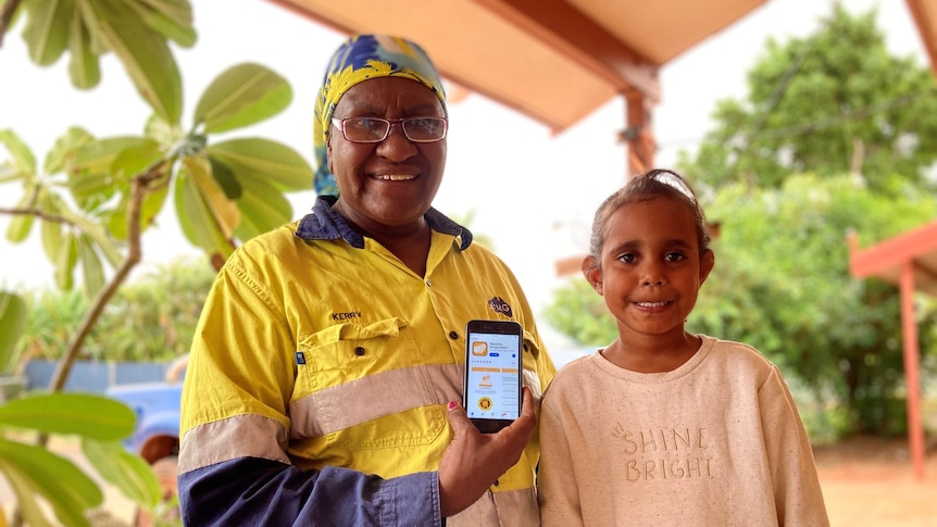 An woman in hi-vis holds an iPhone next to a child.