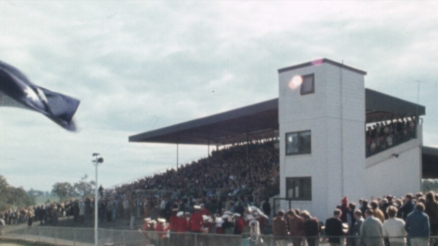 Grainy image of grandstand brimming with people on overcast day