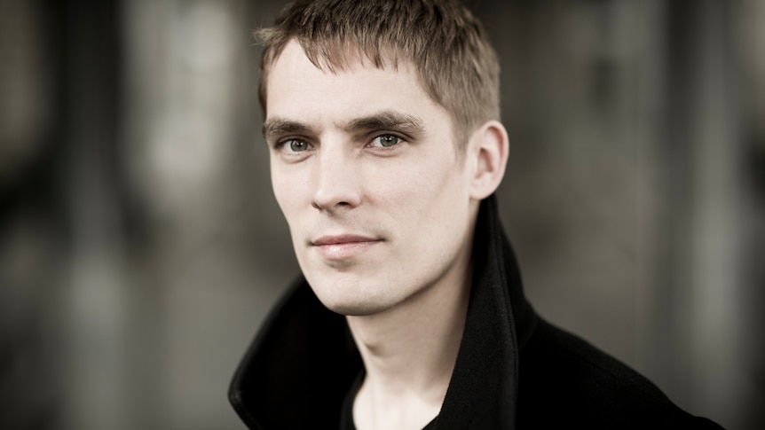 Pianist Cédric Tiberghien looks at the camera against a blurred background
