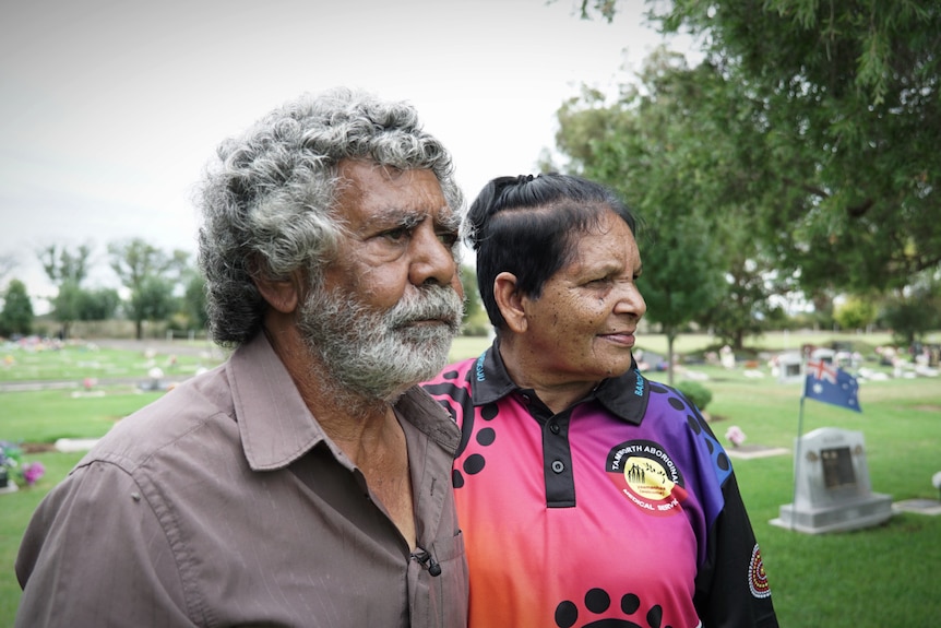 Donald Craigie and Cheryl Fernando stand in a cemetery and look off into the distance.